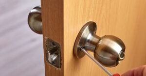 Locksmith unscrews door handle to repair lock