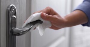 Woman Cleaning Door Handle with Wet Wipe Indoors